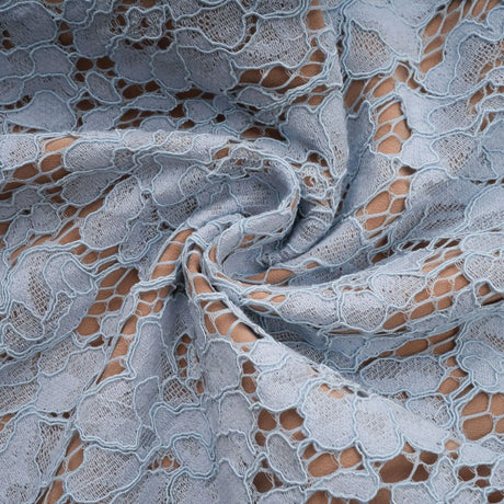 Woman wearing blue floral lace midi dress with boned bodice and fitted silhouette standing against plain background