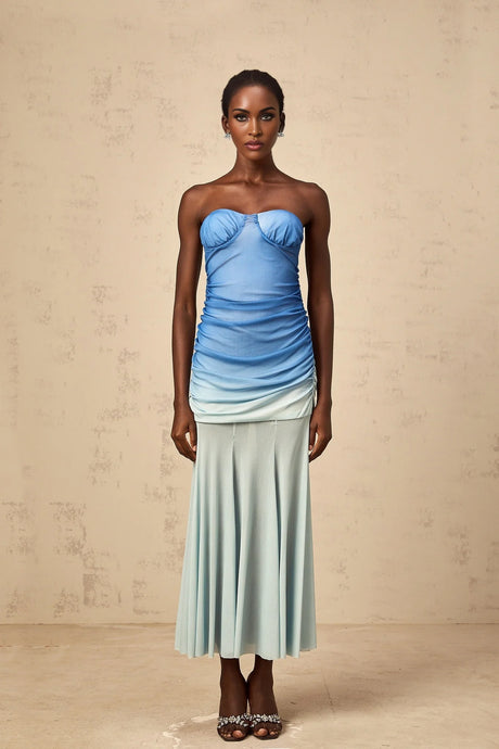 Woman wearing blue gradient mesh midi dress with ombre effect from light to dark blue flowing fabric and sheer details