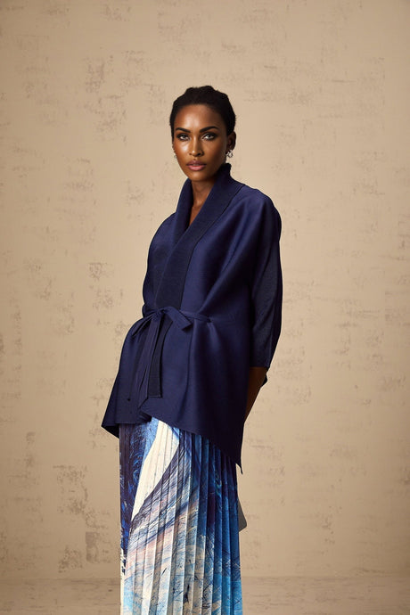Woman wearing blue patterned cape and matching skirt set with crease details and floral print design