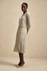 Woman wearing champagne colored knit top and skirt set with vertical stripes in matching pattern