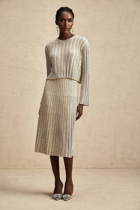 Woman wearing champagne colored knit top and skirt set with vertical stripes matching outfit casual elegant style