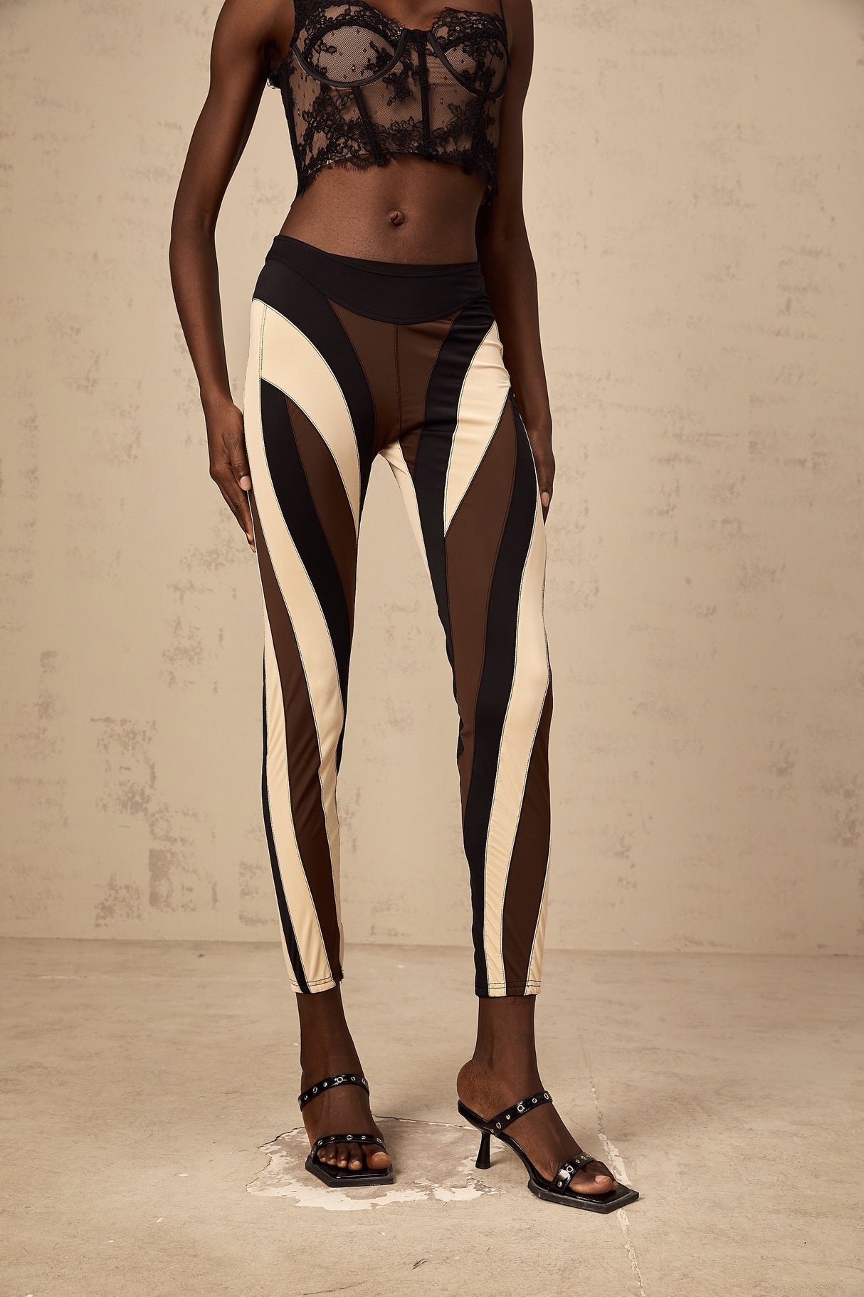 Woman wearing colorful spiral patterned leggings with color block panels in various hues standing in a relaxed pose