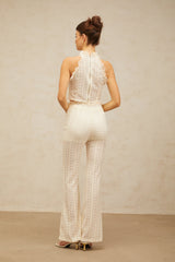 Woman wearing cream white matching set consisting of jacquard top with ruffled lace trim and trousers