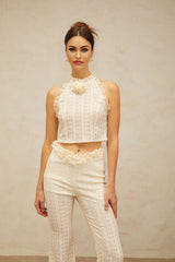 Woman wearing creamwhite matching set with ruffled lace trim top and trousers in jacquard fabric Magali design elegant two piece outfit