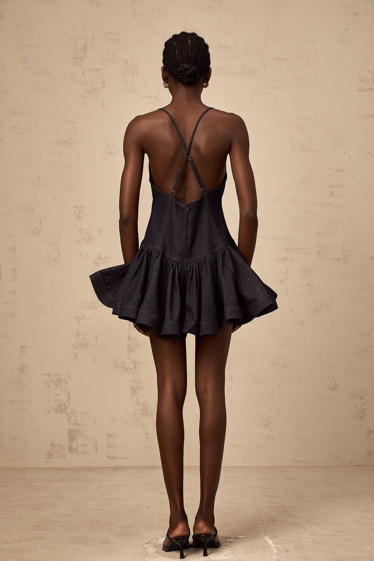 Woman wearing dark blue denim mini dress with flounce detail