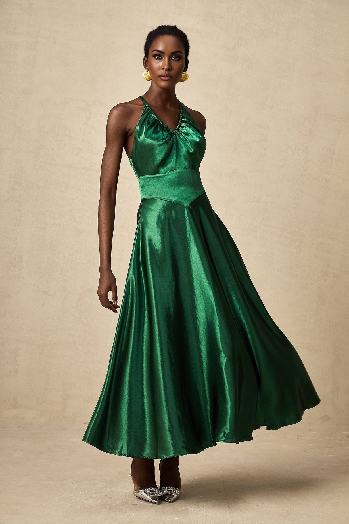 Woman wearing emerald green satin midi dress with open back design