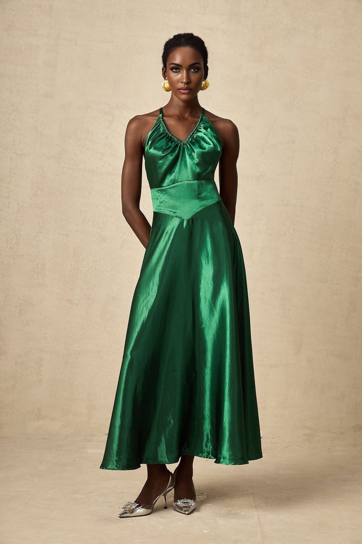 Woman wearing emerald green satin midi dress with open back design
