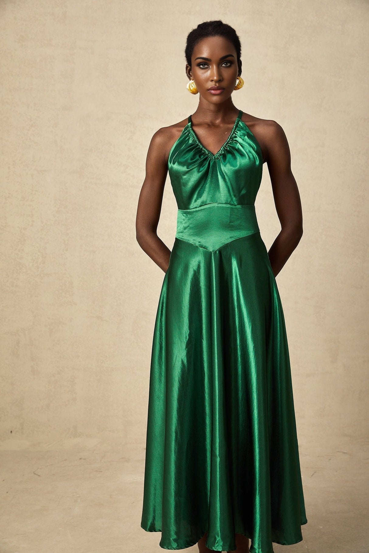 Woman wearing emerald green satin midi dress with open back design