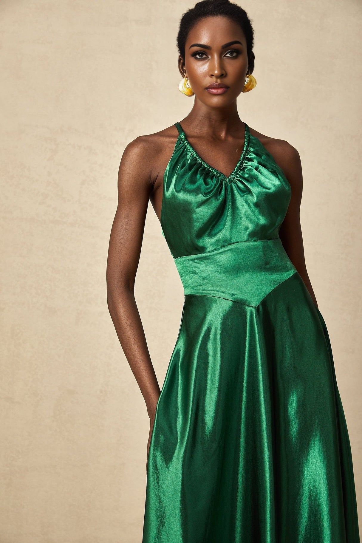 Woman wearing emerald green satin midi dress with open back design