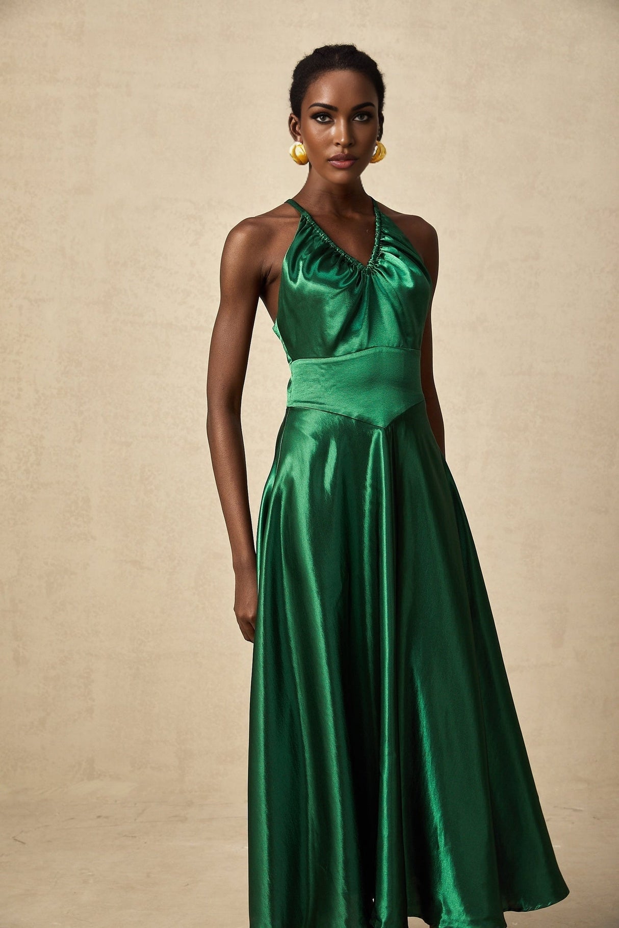 Woman wearing emerald green satin midi dress with open back design