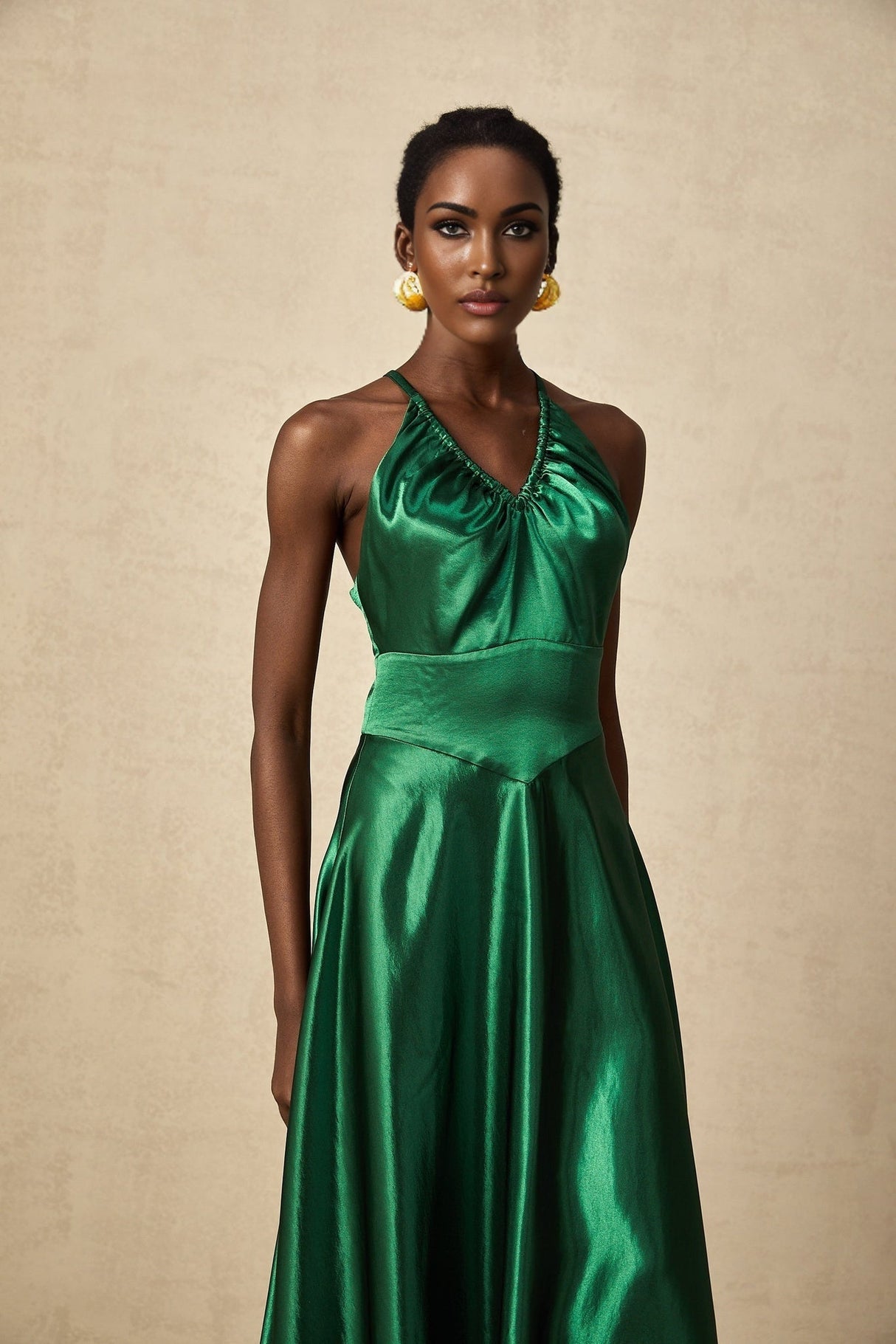 Woman wearing emerald green satin midi dress with open back detail