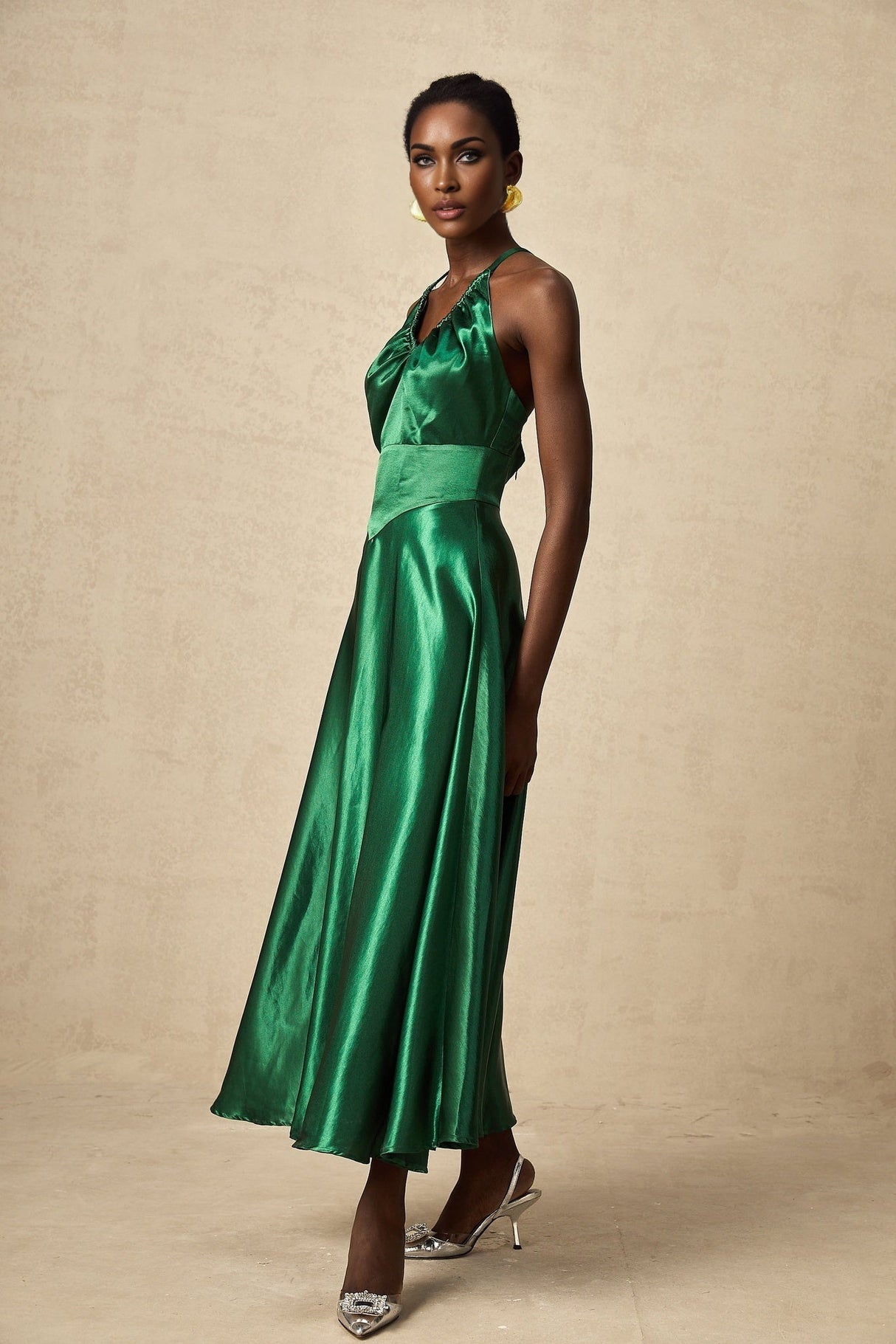 Woman wearing emerald green satin midi dress with open back detail