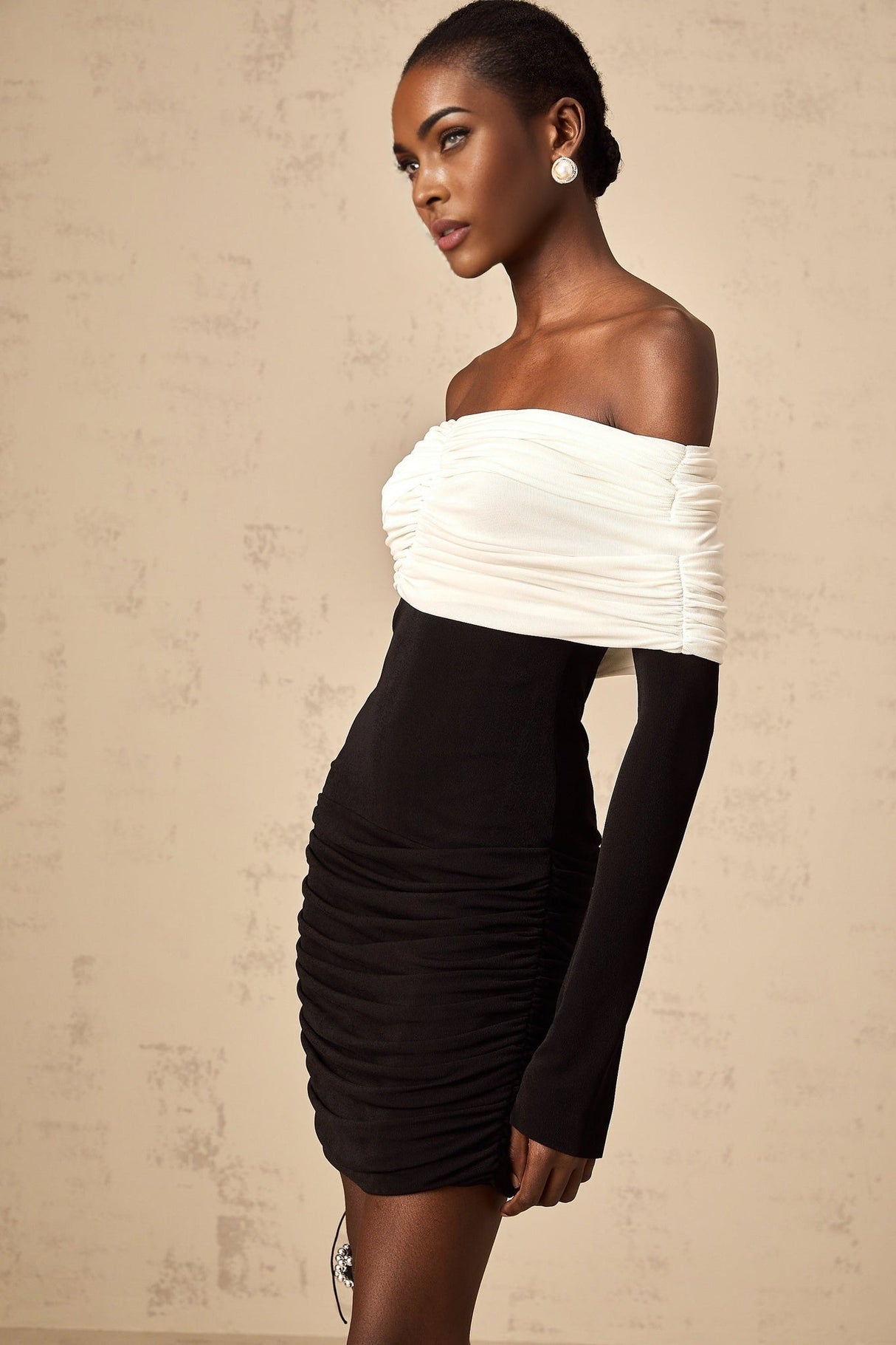 Woman wearing fitted mini dress with colorblocked design ruched details and contrasting panels