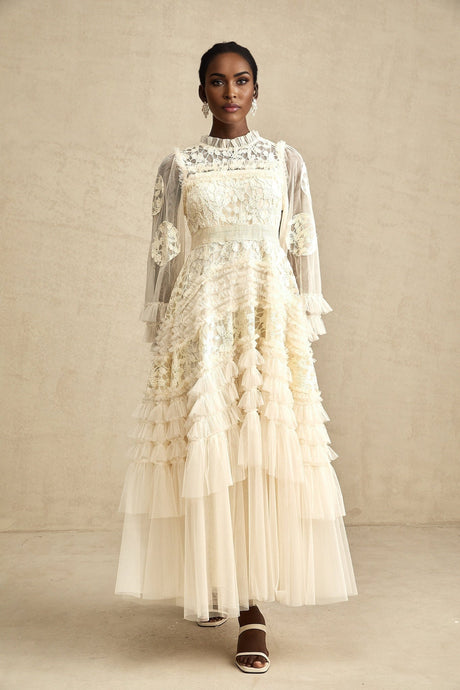 Woman wearing floor length white tulle dress with floral embroidery and layered skirt
