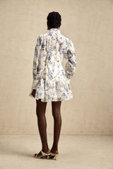 Woman wearing floral print chiffon mini dress with flared skirt and short sleeves standing against plain background