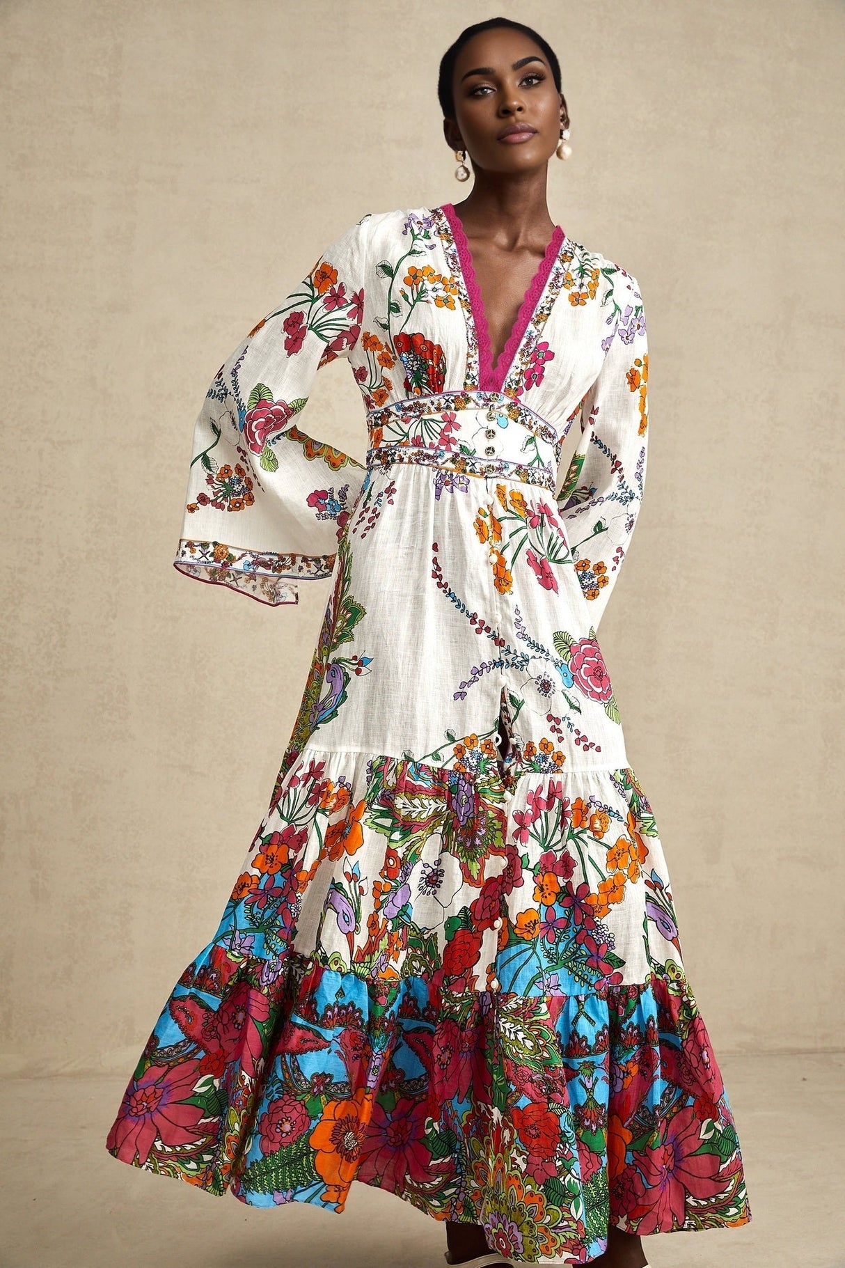 Woman wearing floral print midi dress with Vneck in soft pastel colors standing against plain background