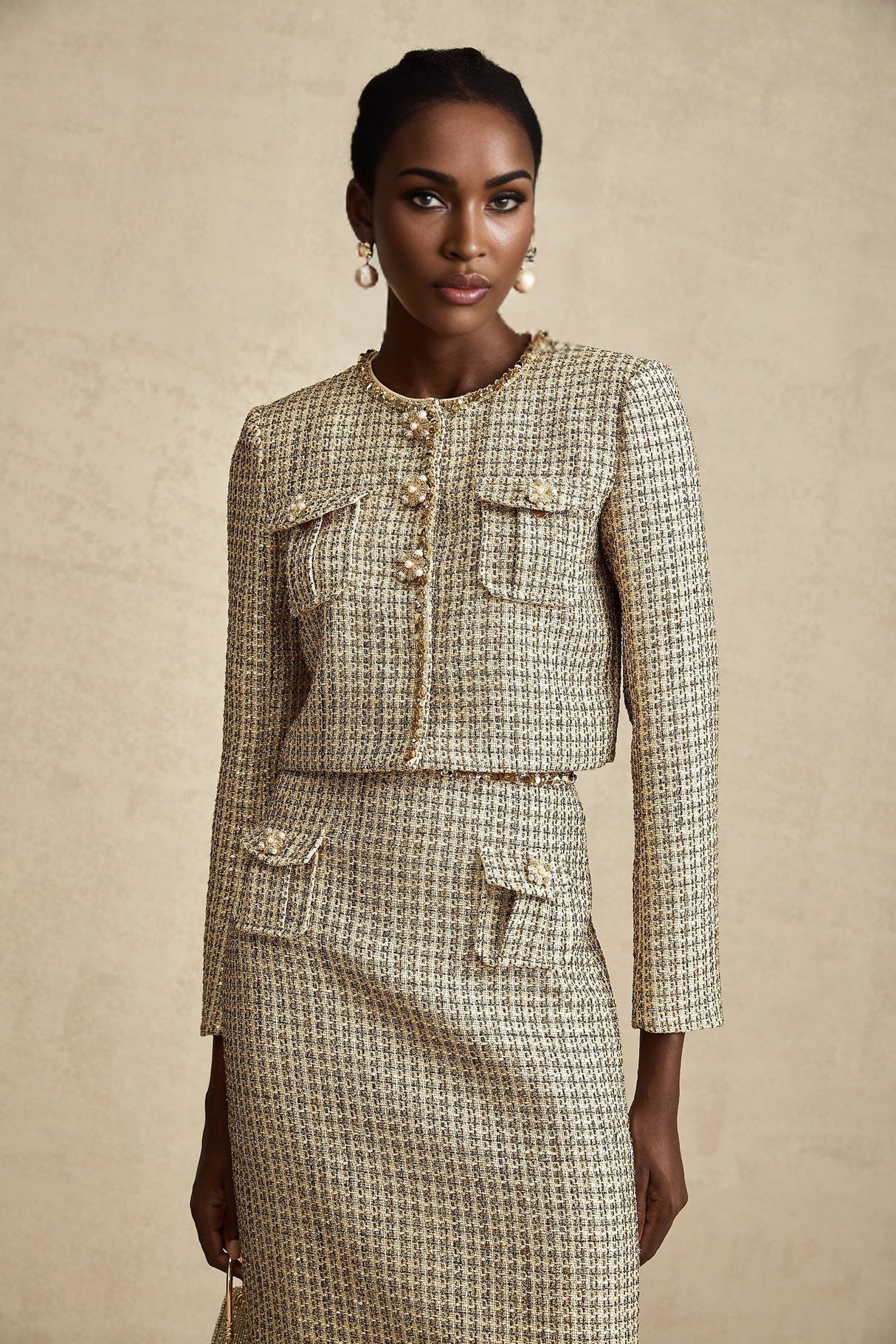 Woman wearing gold tweed jacket and matching skirt with sequin embellishments