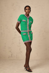 Woman wearing green knitted top and matching skirt set standing in relaxed pose