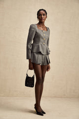 Woman wearing grey herringbone pattern matching set with sleeveless top and shorts standing in casual pose