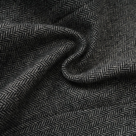 Woman wearing grey herringbone pattern matching set with top and shorts standing against plain background
