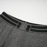 Woman wearing grey herringbone pattern top and matching shorts set standing against plain background