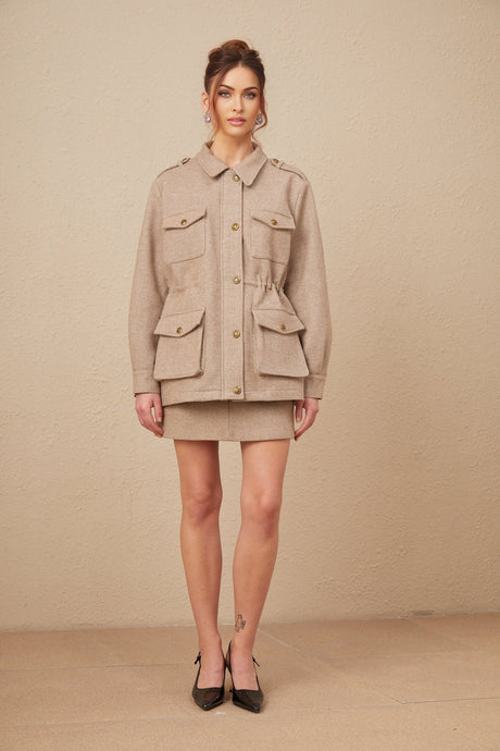 Woman wearing khaki wool twill jacket and matching culottes standing against plain background