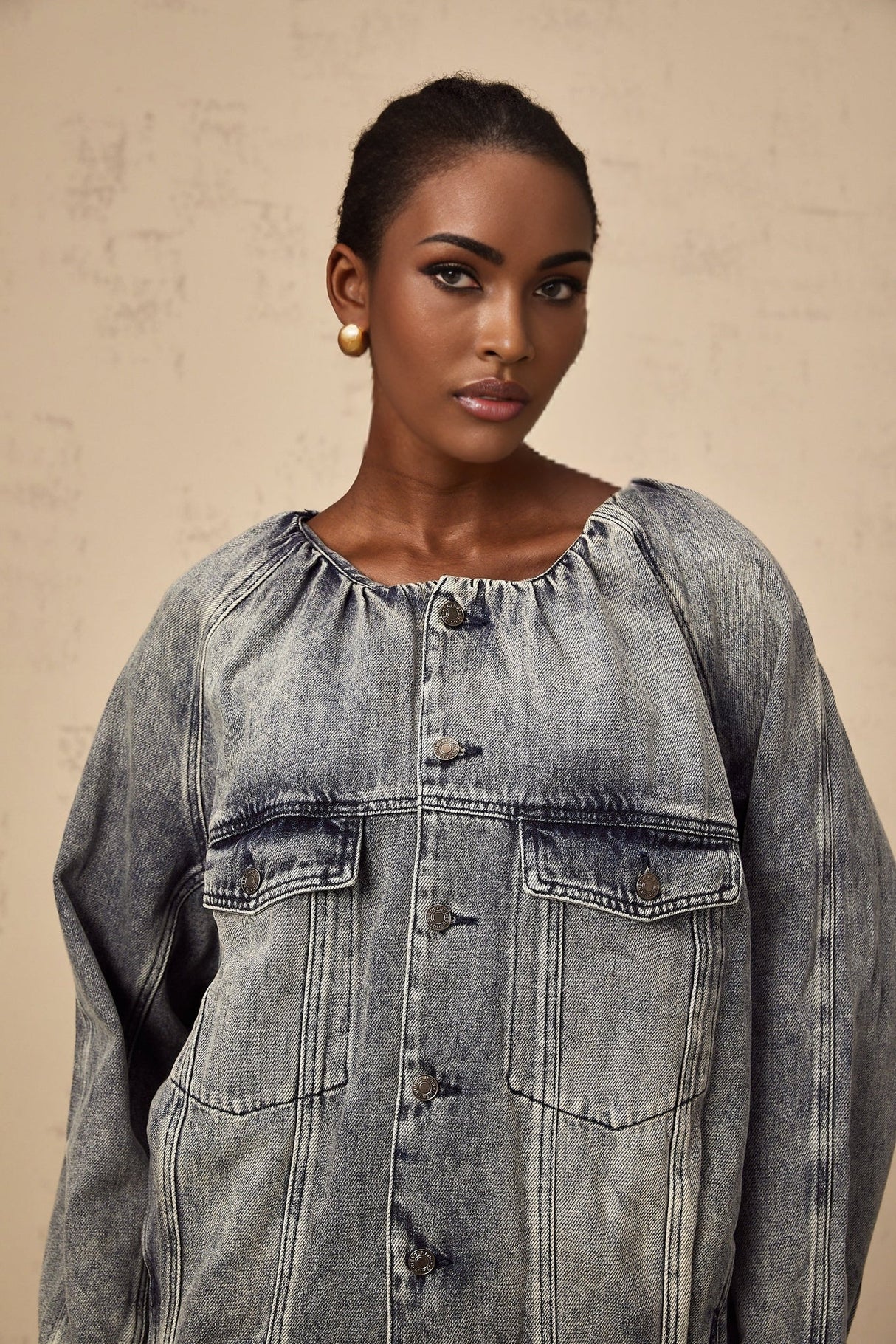 Woman wearing light blue collarless denim jacket with buttoned front and patch pockets