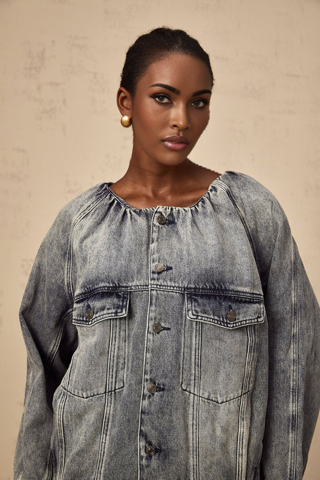 Woman wearing light blue collarless denim jacket with buttoned front and patch pockets
