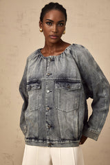 Woman wearing light blue collarless denim jacket with front pockets and button closure