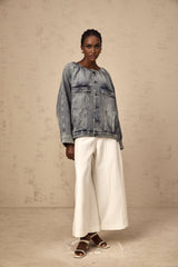 Woman wearing light blue collarless denim jacket with long sleeves and button front closure