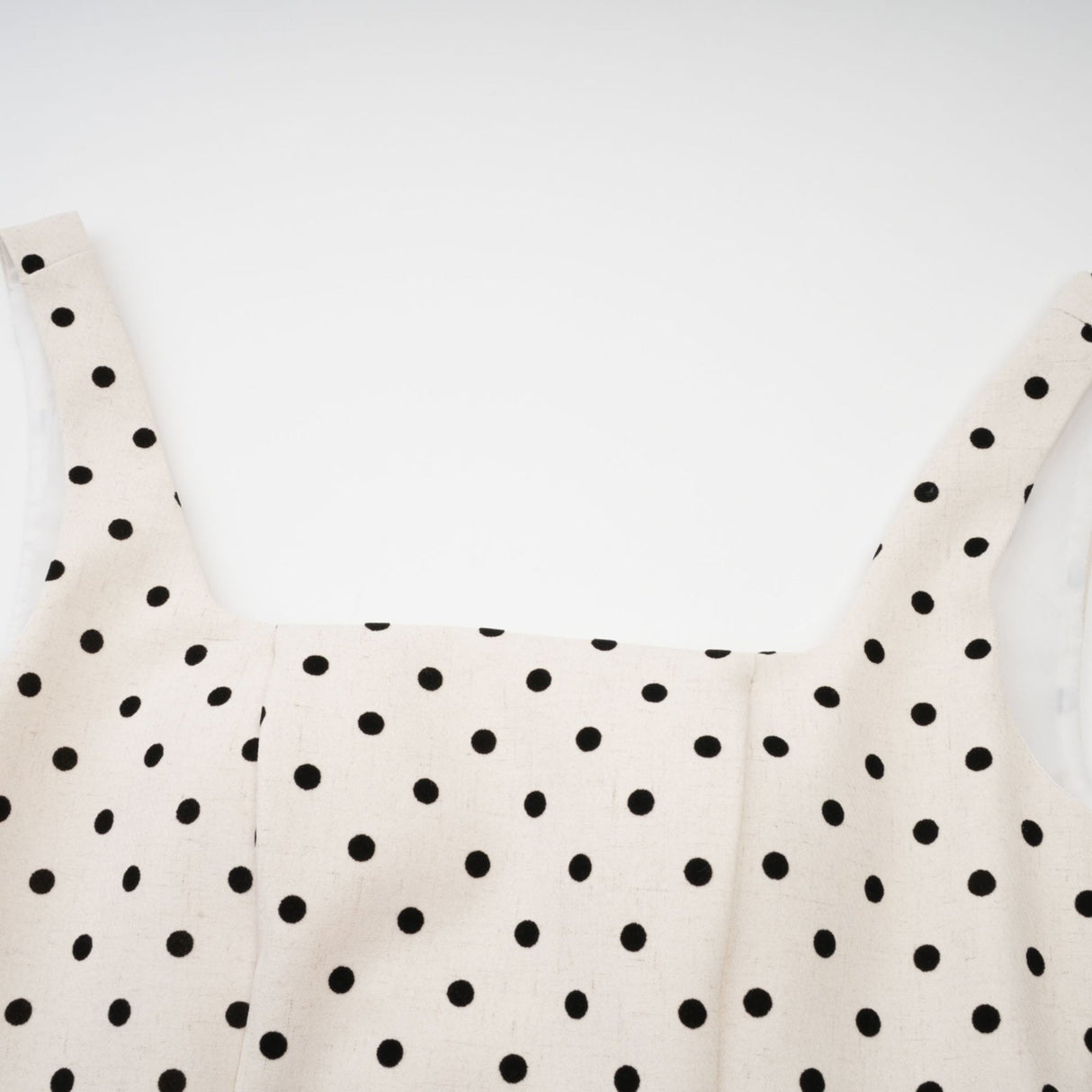 Woman wearing light colored polka dot mini dress with puffed sleeves and gathered skirt