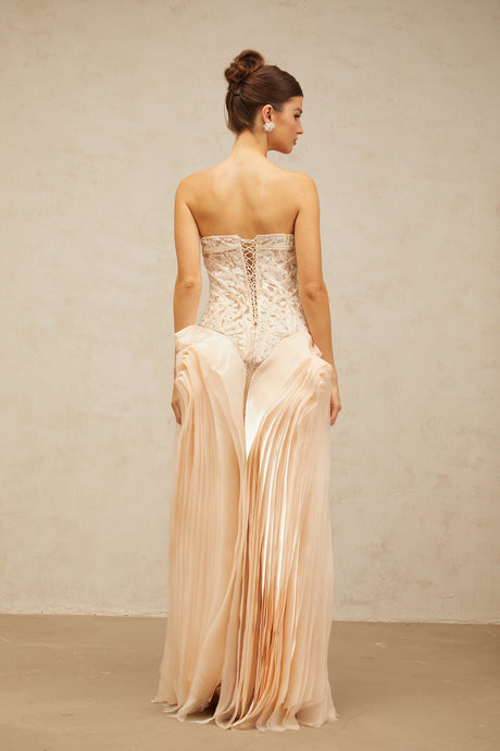 Woman wearing long beige lace dress with corset bodice and layered skirt