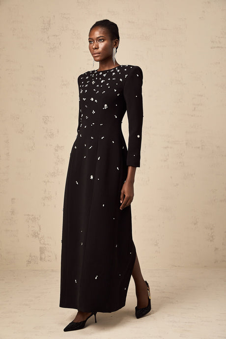 Woman wearing long black evening gown with crystal embellishments and flowing skirt