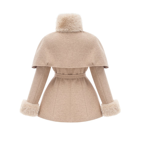 Woman wearing long black faux fur coat with detachable cape feature standing against plain background
