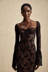 Woman wearing long black lace maxi dress with flared skirt and fitted bodice standing in neutral background