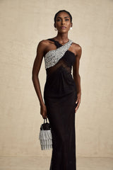 Woman wearing long black maxi dress with crossover bodice and crystal embellishments
