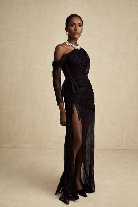 Woman wearing long black maxi dress with one shoulder strap and side cutout detail