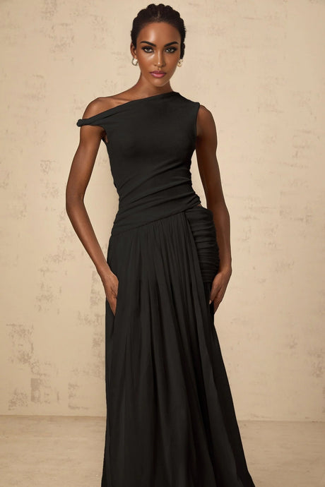 Woman wearing long black maxi dress with single shoulder strap and gathered fabric panel