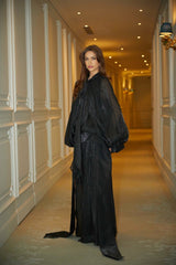 Woman wearing long black pleated satin maxi dress with flowing skirt and fitted bodice