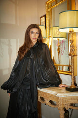 Woman wearing long black pleated satin maxi dress with flowing skirt and fitted bodice