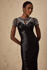 Woman wearing long black sequined maxi dress with cutout details