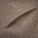 Woman wearing long brown wool coat with fur trim and belt cinched at waist cape style drapes over shoulders