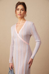 Woman wearing long burgundy knit dress with pleated skirt and V neckline