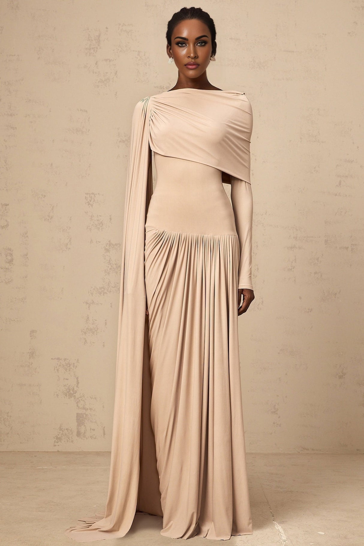 Woman wearing long flowing neutral colored maxi dress with ribbon design details and draped silhouette