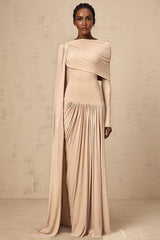 Woman wearing long flowing neutral colored maxi dress with ribbon design details and draped silhouette