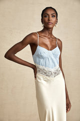 Woman wearing long flowing white maxi dress with lace trim and panelled design