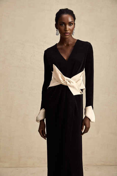 Woman wearing long flowy maxi dress with contrasting color and large bow detail at v neckline