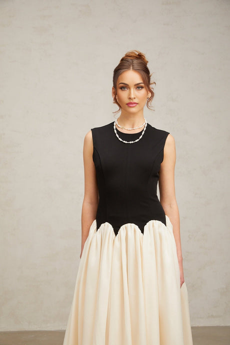 Woman wearing long flowy maxi dress with puffed sleeves and color block design in multiple shades