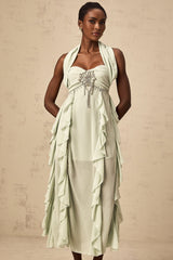 Woman wearing long flowy midi dress with embellished details and ruffled accents
