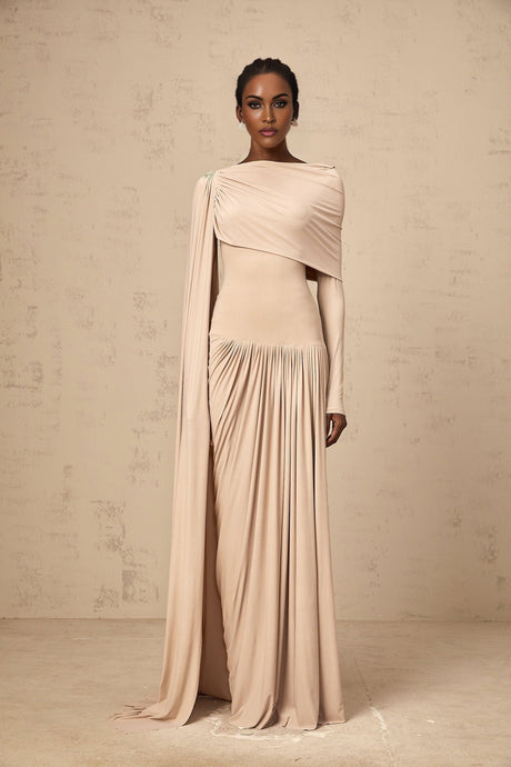 Woman wearing long flowy neutral colored maxi dress with ribbon design details and draped fabric